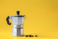 Italian coffee maker and roasted coffee beans  on yellow paper background Royalty Free Stock Photo