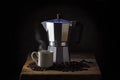 Italian coffee maker, steaming cup and whole coffee beans on rustic wood, dark background, copy space on each side Royalty Free Stock Photo
