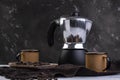 Italian coffee maker and two coffee mugs with roasted coffee beans in wooden container