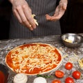 Italian Cuisine. Cook Hand Adding Grated Cheese To Pizza