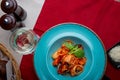 Italian cuisine. Pasta with seafood, tomatoes and cheese in a blue, a fork and a knife on a light background. Royalty Free Stock Photo