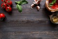 Italian Cuisine. Tomato, basil, garlic and tomato sauce on the dark wooden table top view, with copy space Royalty Free Stock Photo