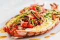 Italian cuisine. Whole lobster baked and sliced in half Served with tomato salad and sauce on white plate