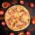 Italian delicious pizza with ingredients and spices on dark background. Flat lay, top view.