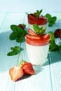 Italian dessert Panakota with strawberry coolies, fresh berries and mint on a blue background with hard shadows. Creamy milk Royalty Free Stock Photo