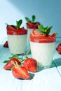 Italian dessert Panakota with strawberry coolies, fresh berries and mint on a blue background with hard shadows. Creamy milk