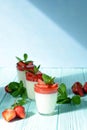 Italian dessert Panakota with strawberry coolies, fresh berries and mint on a blue background with hard shadows. Creamy milk Royalty Free Stock Photo