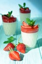 Italian dessert Panakota with strawberry coolies, fresh berries and mint on a blue background with hard shadows. Creamy milk