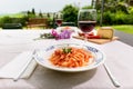 Italian dish, handmade spaghetti pasta, pici with tomato sauce on a table in the garden outdoors
