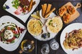 Italian dishes on the table including Burrata Salad, Baked Cod with sauce, Spaghetti Carbonara, Baked scallops with cheese. Royalty Free Stock Photo