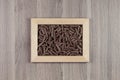 Italian dry brown twisted wholegrain pasta in wooden frame on beige wooden board as decorative picture background.