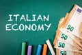Italian Economy. Text and euro money on a green chalkboard