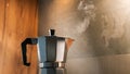 An Italian espresso mokka machine with steam getting out of it while making a fresh coffee in a regular kitchen with wood and ston Royalty Free Stock Photo