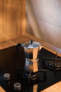 An Italian espresso mokka machine with steam getting out of it while making a fresh coffee in a regular kitchen with wood and ston