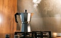 An Italian espresso mokka machine with steam getting out of it while making a fresh coffee in a regular kitchen with wood and ston