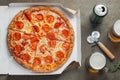 Italian fast food. Delicious hot pepperoni pizza in a box, and glass of beer sliced and served on brown table, close up Royalty Free Stock Photo