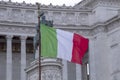 Italian flag against the background of the Vittoriano monument with a equestrian statue of King Vittorio Emanuele II in Rome, Royalty Free Stock Photo