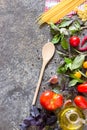 Italian food background, with different tomatoes, basil, spaghetti, olive oil, garlic and wooden spoon. Royalty Free Stock Photo