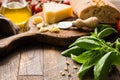 Italian food background with parmesan cheese, olive oil, ciabatta and basil leaves on rustic wood