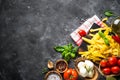 Pasta, tomatoes, cheese, basil and olive oil on black stone tabl Royalty Free Stock Photo