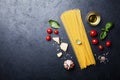 Italian food background with uncooked spaghetti, tomato, basil leaves, cheese, garlic and olive oil for cooking pasta Royalty Free Stock Photo