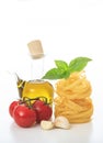 Italian food concept. ÃÂ¤agliatelle nests pasta, basil, tomatoes, olive oil and garlic on white background Royalty Free Stock Photo
