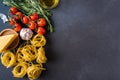 Pasta and Ingredients for cooking on dark background, top view. Pasta, tomatoes, garlic, rosemary, peppers Royalty Free Stock Photo