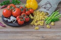 Italian food cooking ingredients on wooden background, dry pasta, vegetables, fresh tomatoes, asparagus, bell pepper Royalty Free Stock Photo