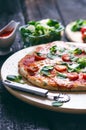 Italian food, cuisine. Margherita pizza on a black, wooden table with igredients like tomatoes, salad, cheese, mozzarella, basil. Royalty Free Stock Photo