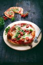 Italian food, cuisine. Margherita pizza on a black, wooden table with igredients like tomatoes, salad, cheese, mozzarella, basil. Royalty Free Stock Photo