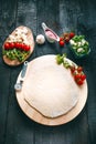 Italian food, cuisine. Margherita pizza on a black, wooden table with igredients like tomatoes, salad, cheese, mozzarella, basil. Royalty Free Stock Photo