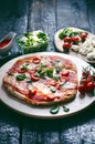 Italian food, cuisine. Margherita pizza on a black, wooden table with igredients like tomatoes, salad, cheese, mozzarella, basil. Royalty Free Stock Photo