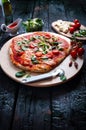 Italian food, cuisine. Margherita pizza on a black, wooden table with igredients like tomatoes, salad, cheese, mozzarella, basil. Royalty Free Stock Photo