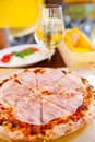 Italian food dinner. Pizza with tomato prosciutto mozzarella glass white wine summer outdoor restaurant Royalty Free Stock Photo