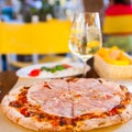Italian food dinner. Pizza with tomato prosciutto mozzarella glass white wine summer outdoor restaurant Royalty Free Stock Photo