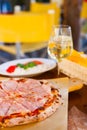 Italian food dinner. Pizza with tomato prosciutto mozzarella glass white wine summer outdoor restaurant Royalty Free Stock Photo