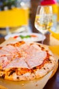 Italian food dinner. Pizza with tomato prosciutto mozzarella glass white wine summer outdoor restaurant Royalty Free Stock Photo