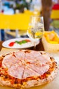 Italian food dinner. Pizza with tomato prosciutto mozzarella glass white wine summer outdoor restaurant Royalty Free Stock Photo