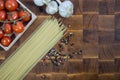 Cherry tomatoes, pasta spaghetti, garlic, and pepper on wooden brownn handmade cutting board