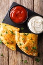 Italian food: pizza calzone with meat, vegetables and cheese close-up. Vertical top view Royalty Free Stock Photo