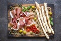 Italian food, prosciutto, grissini, smoked sausage, ham, olives, capers, sun-dried tomatoes on wooden background