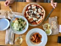 Italian Food Table with Penne Pasta, Funghi Mushroom Pizza, Parmesan Cheese Salad and White Wine at Local Restaurant