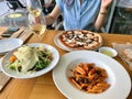 Italian Food Table with Penne Pasta, Funghi Mushroom Pizza, Parmesan Cheese Salad and White Wine at Local Restaurant