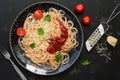 Italian food, traditional pasta spaghetti with tomato sauce, parmesan cheese and greens on a black stone background. Top view, Royalty Free Stock Photo