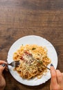 Italian food. woman hand holding fork with spaghetti bolognese in white plate on wooden table. with copy space Royalty Free Stock Photo