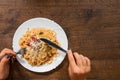 Italian food. woman hand holding fork with spaghetti bolognese in white plate on wooden table. with copy space Royalty Free Stock Photo