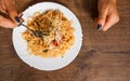 Italian food. woman hand holding fork with spaghetti bolognese in white plate on wooden table. with copy space Royalty Free Stock Photo