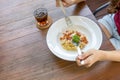 Italian food. woman hand holding fork and spoon with spaghetti carbonara in white plate on wooden table. top view. with copy space Royalty Free Stock Photo