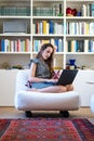 Girl sitting on an armchair writes on her computer Royalty Free Stock Photo