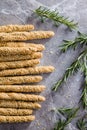 Italian grissini bread sticks with sesame seeds and rosemary on kitchen table. Top view